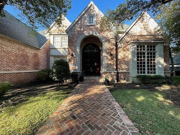 View of front of home with brick siding, a front lawn, and french doors