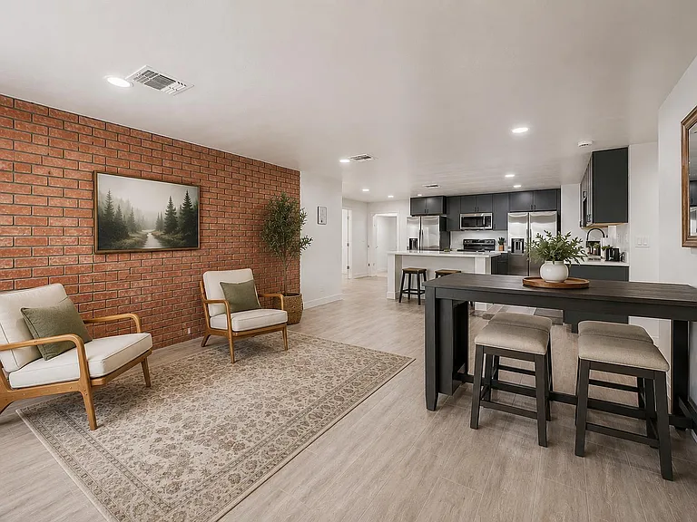 Open-concept living and dining area flows into a full kitchen with stainless appliances, breakfast bar seating, and ample cab