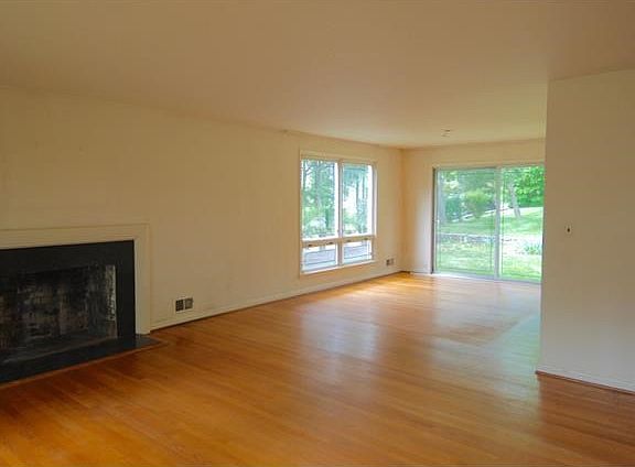 Bright living room with view towards dining room with oversized windows and sliding glass doors to l