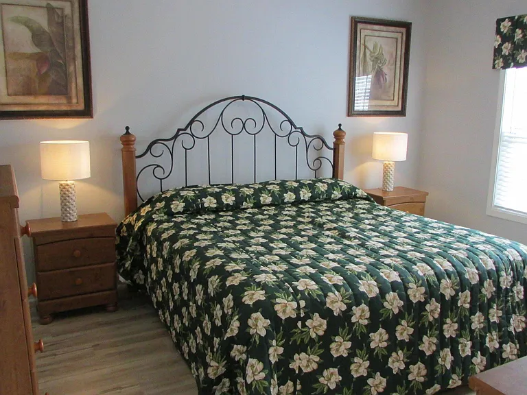 Master bedroom with King bed, chest, dresser with mirror and view to golf course.