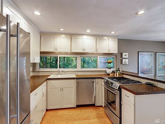 The updated kitchen has white shaker cabinets, leathered counter tops, stainless steel appliances including a gas stove and unde