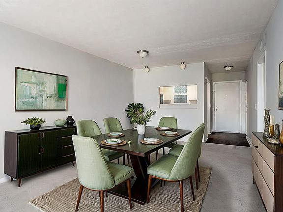 Elegant dining room with a modern green theme, featuring a stylish dark wood table, matching chairs, minimalist decor, and contemporary artwork.