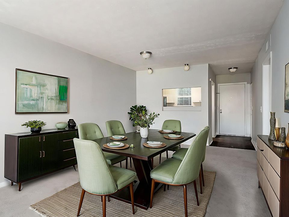 Elegant dining room with a modern green theme, featuring a stylish dark wood table, matching chairs, minimalist decor, and contemporary artwork.