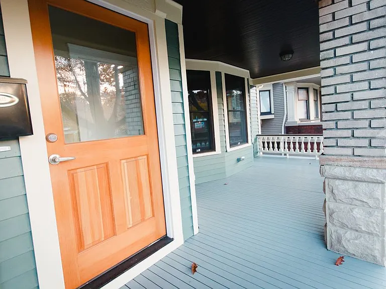 Large covered front porch shaded by an oak tree in the front yard