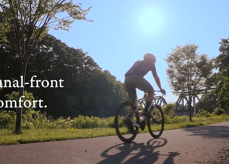 A person riding a bicycle on the Erie Canal path near Westport Crossing in Pittsford, NY