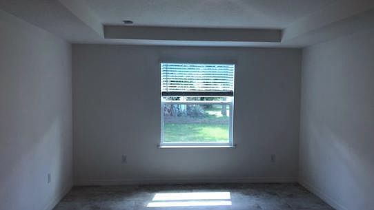 Large master bedroom with a tray ceiling and tiled floors
