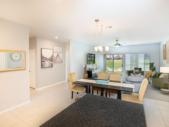 Looking into dining area and living room from kitchen with sliders going out to back patio and golf course.