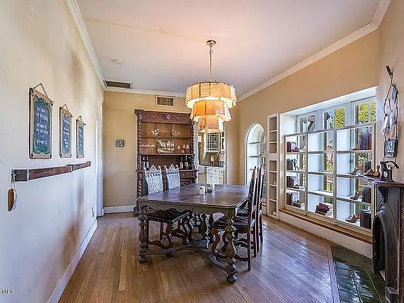 Dining room with large windows that can be opened behind the built-in storage shelving and vintage fireplace with cast iron surround.