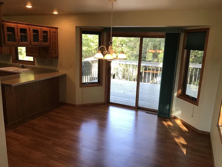 Dining room with view of deck, woods with sliding and screen door.