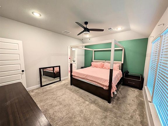 Carpeted bedroom featuring visible vents, baseboards, a ceiling fan, and lofted ceiling