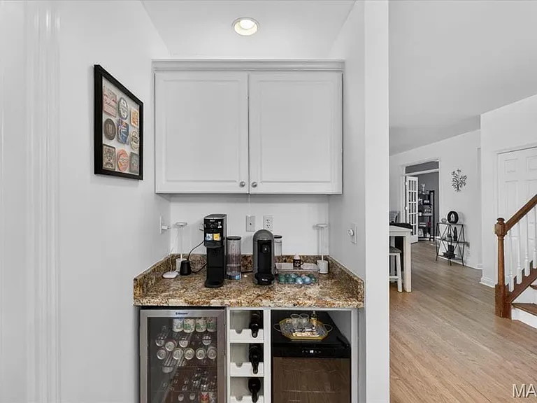 Built-in beverage station featuring white cabinetry, a stone-finish countertop, and integrated wine storage