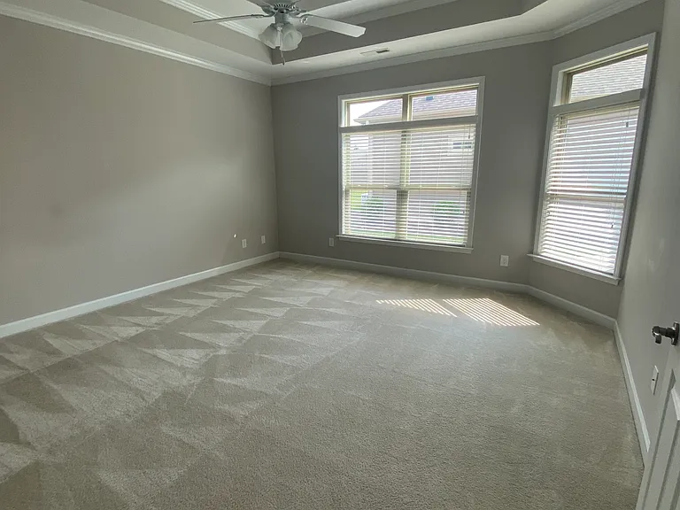 master bedroom with vaulted ceilings, plush carpeting and plenty of natural light