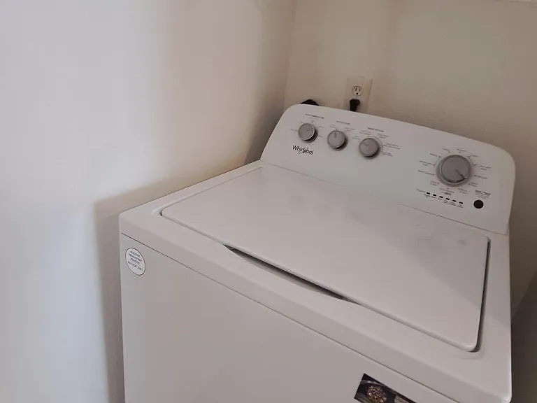 Convenient laundry nook with a top-load washer and open wire shelving for detergent and supplies.