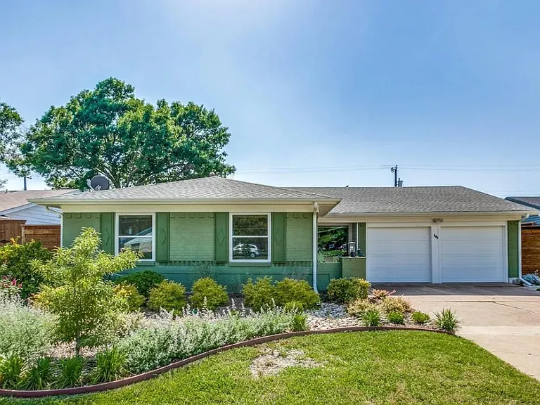 Front yard with 2 car garage and lush landscaping