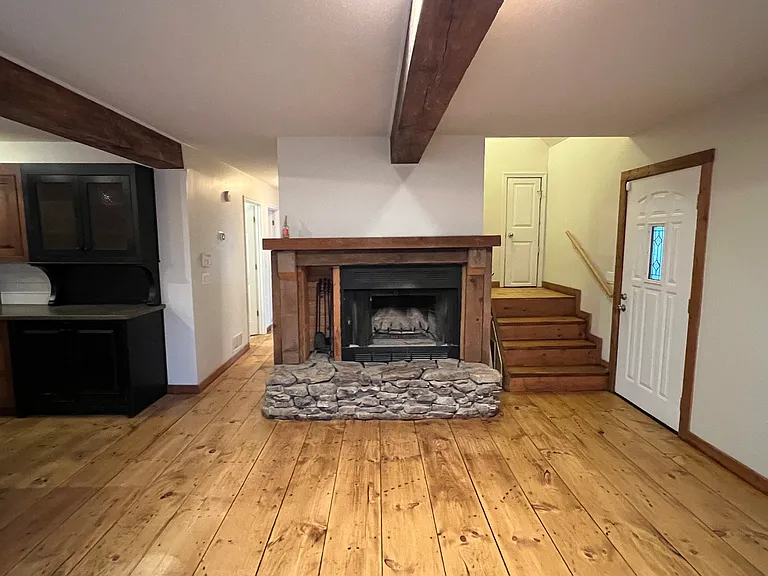 Wood burning fireplace on main level. Left side hall leads to two bedrooms and to the right of fireplace is stairs that lead to upstairs bedrooms.