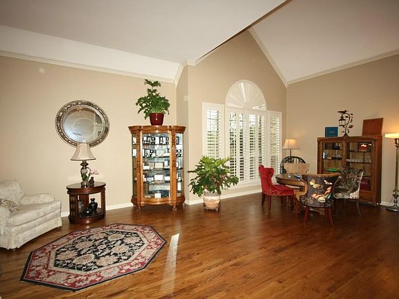 Open concept living and dining rooms with vaulted ceilings, hardwood floors, crown moldings, plantat