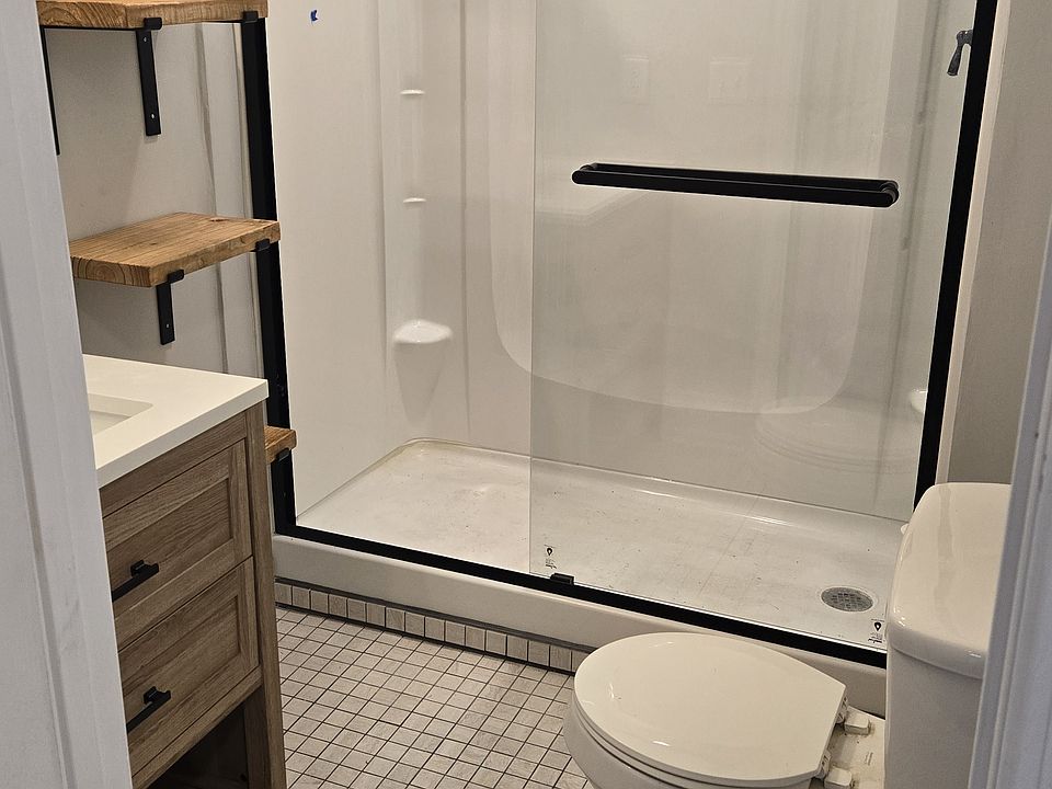 Newly renovated bathroom with modern shelving, glass door and new vanity.