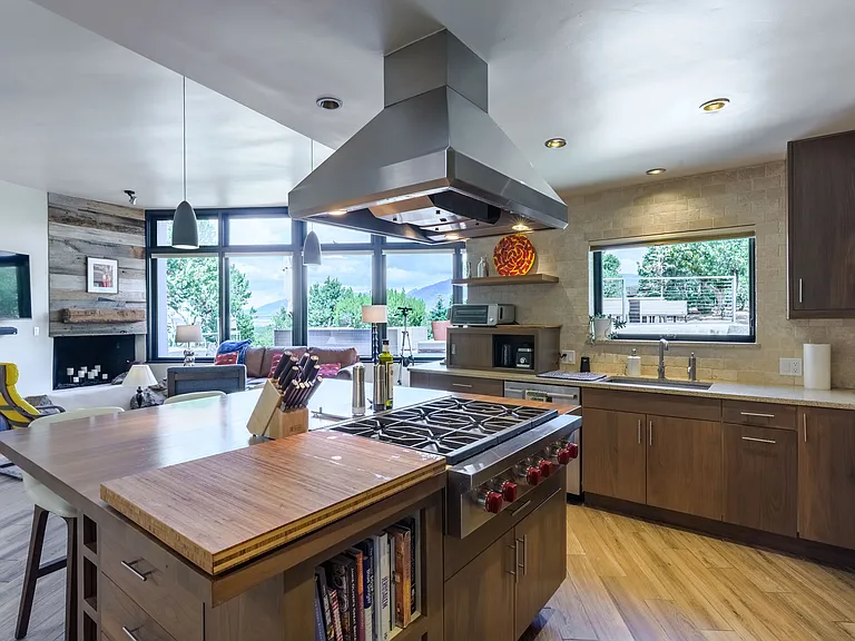 Kitchen island and sink with view to the back porch, junipers, and pinons