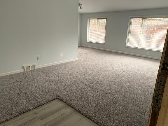 Living room with updated blinds, flooring including carpet and laminate at the entrance
