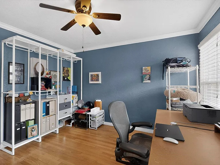 A bright room with a ceiling fan and a wide window, designed for comfort.