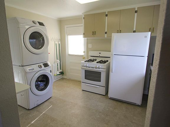 Kitchen: East wall, showing in-unit laundry, back door, gas range, and refrigerator.