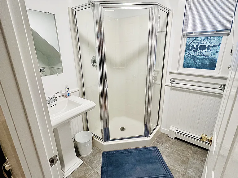 Studio apartment bathroom with shower, hair dryer, etc.