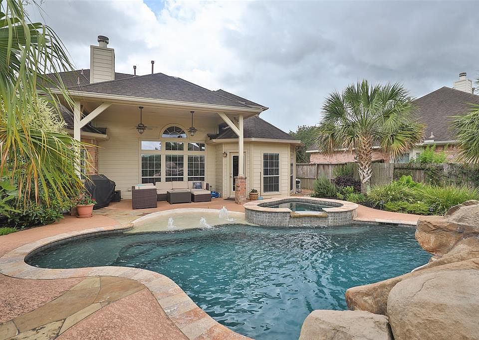 Stunning back yard featuring this elegant winding pool with travertine coping and accents, elevated spa and water feature.