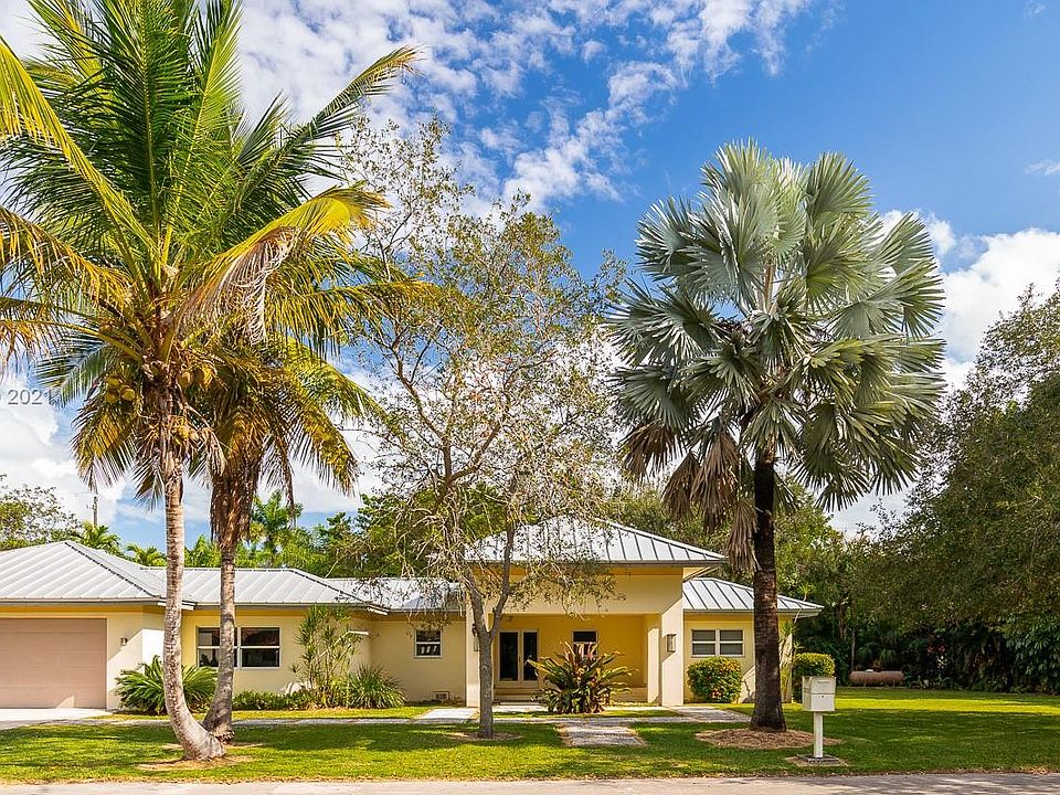 The Frontal Elevation shows the distinctive Metal Roof, The Grand entrance, the wide lot, the beautiful Oak trees and Palms, and notice the height and width of the 2 Car+ Garage that has its own office & Bath. ALSO, ALL THE WINDOWS AND DOORS IN THIS HOME 