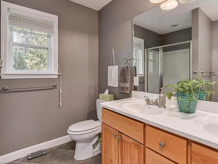 Main floor bathroom across from primary bedroom has a double sink, good storage, and spacious shower.