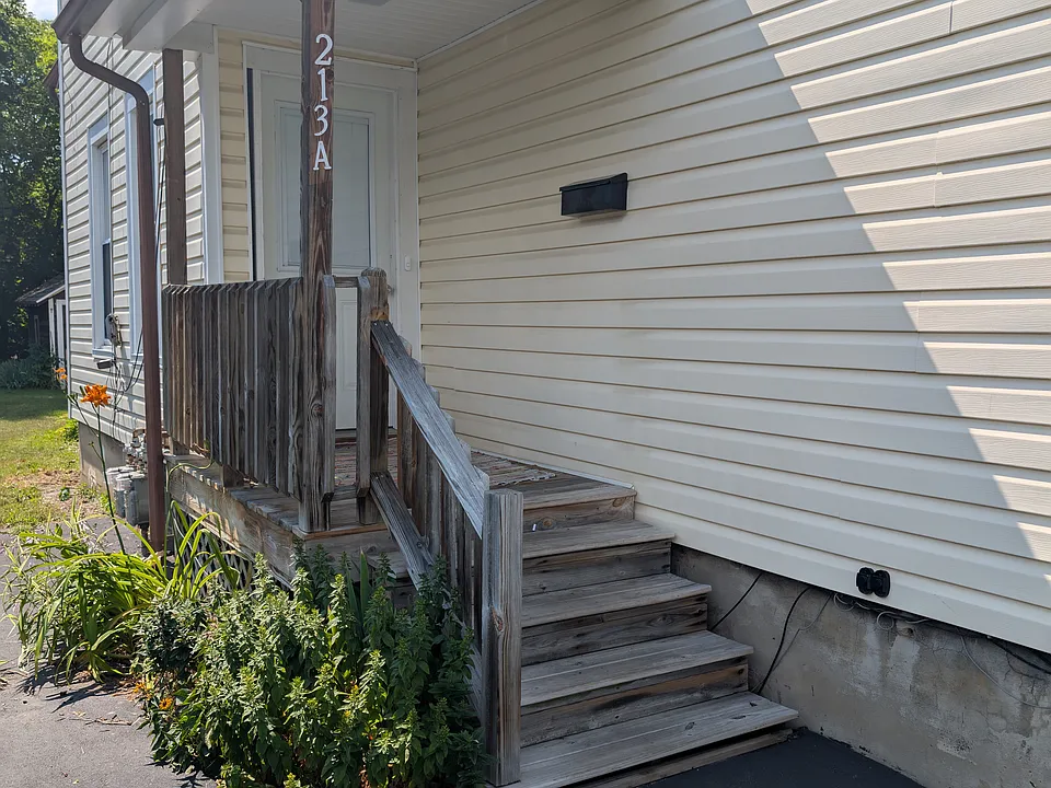 Exterior entrance with small porch. Black topped driveway for off street parking. Landscaped along porch.