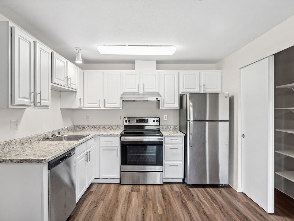 Bright, modern kitchen featuring white cabinetry, stainless steel appliances, and durable wood-style flooring.