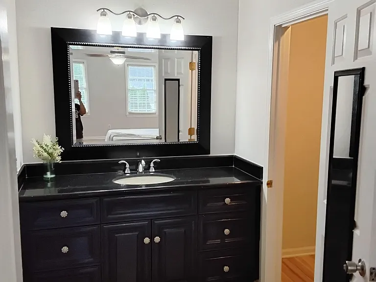 Spacious vanity area with a long countertop, abundant drawer storage, and a large framed mirror with overhead lighting.