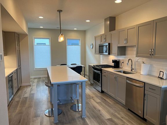 Kitchen with island, breakfast bar, table, wine refrigerator and all appliances.