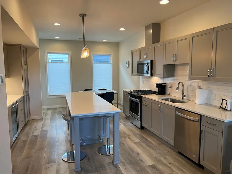 Kitchen with island, breakfast bar, table, wine refrigerator and all appliances.