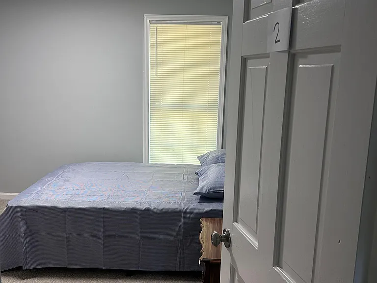 Private bedroom featuring neutral finishes, carpeted flooring, and a window with blinds for light control and privacy.