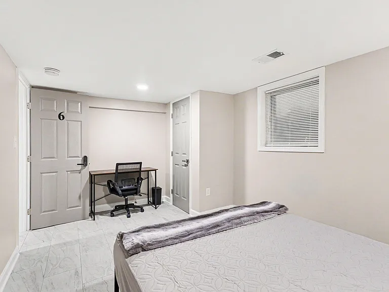 Private bedroom with tiled flooring, a window with blinds, and space for a desk setup for work or study.