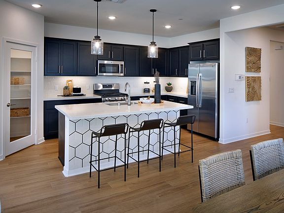 A modern and stylish kitchen with dark cabinets, a white island with a geometric pattern, and pendan