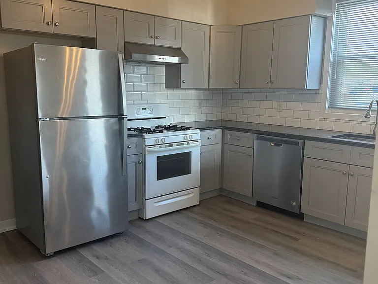 View of Eat in Kitchen with refrigerator, dishwasher, garbage disposal, granite countertop, with view of living room.