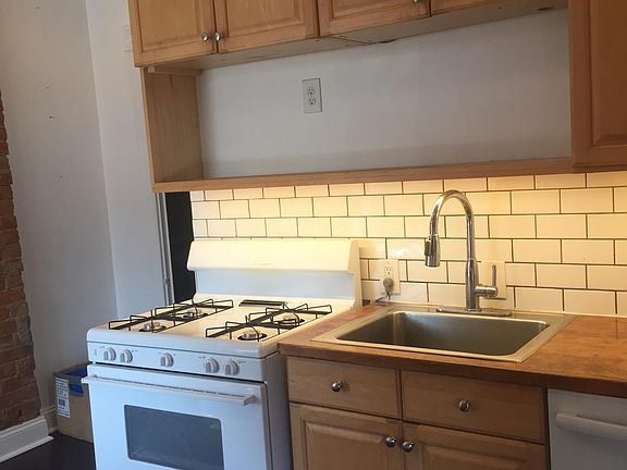 kitchen with dishwasher, gas stove, ceiling fan, exposed brick walls