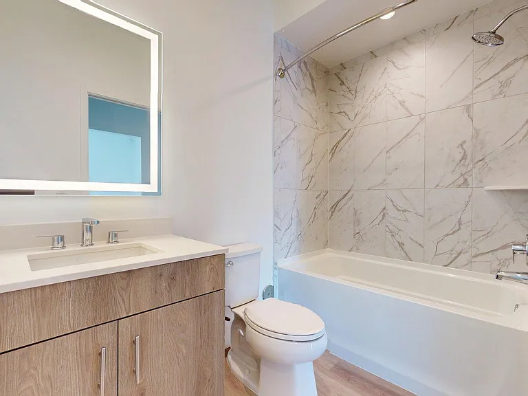 Apartment Bathroom with large soaking tub, LED vanity mirror and Wood Style Flooring.