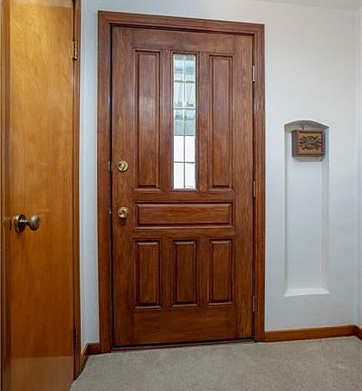 BEAUTIFUL WOODEN FRONT DOOR HAS BEEN STAINED AND HIGHLY POLISHED COMPLETING THE LOVELY ENTRYWAY.