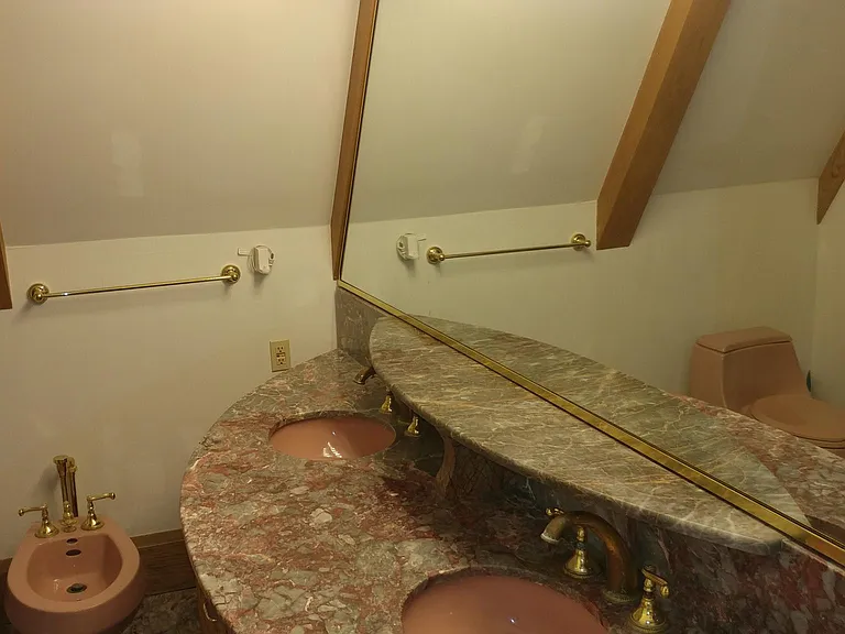 Master bathroom with a marble double-sink vanity, large mirror, and vaulted ceiling with exposed beams.