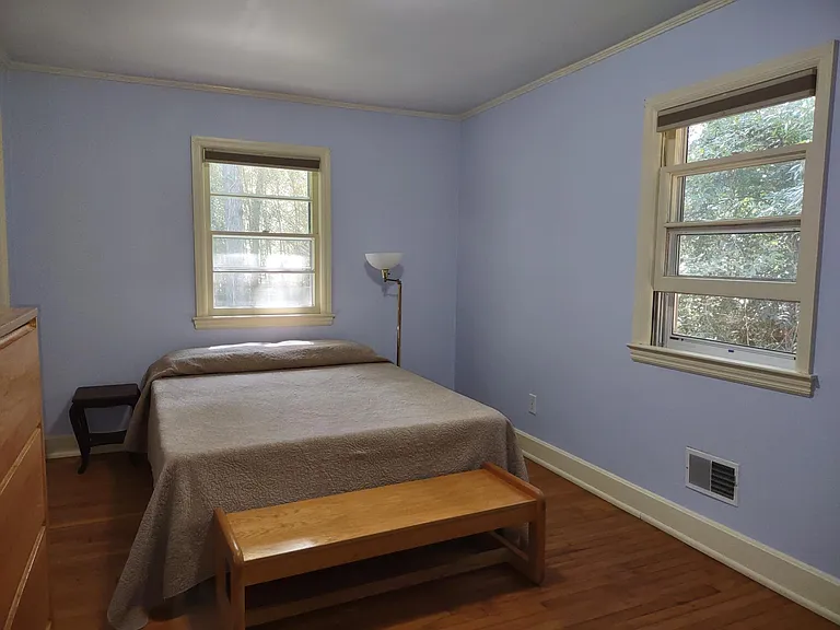 Main bedroom has queen bed, dresser, desk, chair, and foot-of-the-bed bench.