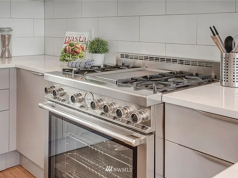 The sleek high-end kitchen features chef's grade stainless steel appliances, marble casual counters, plentiful cabinets and a wine fridge.