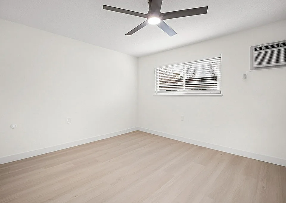 Spacious, sunlit bedroom featuring a ceiling fan and air conditioning