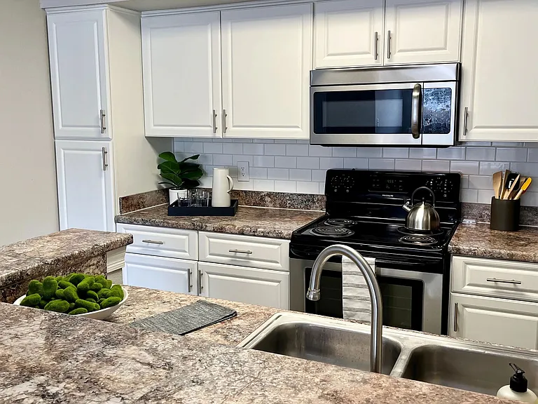 Kitchens that inspire gatherings with a granite-style countertop breakfast bar and modern stainless-steel appliances.