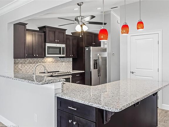 Kitchen with wood cabinetry with easy close drawers, granite counter tops, stainless steel appliances, pendant lighting and brea