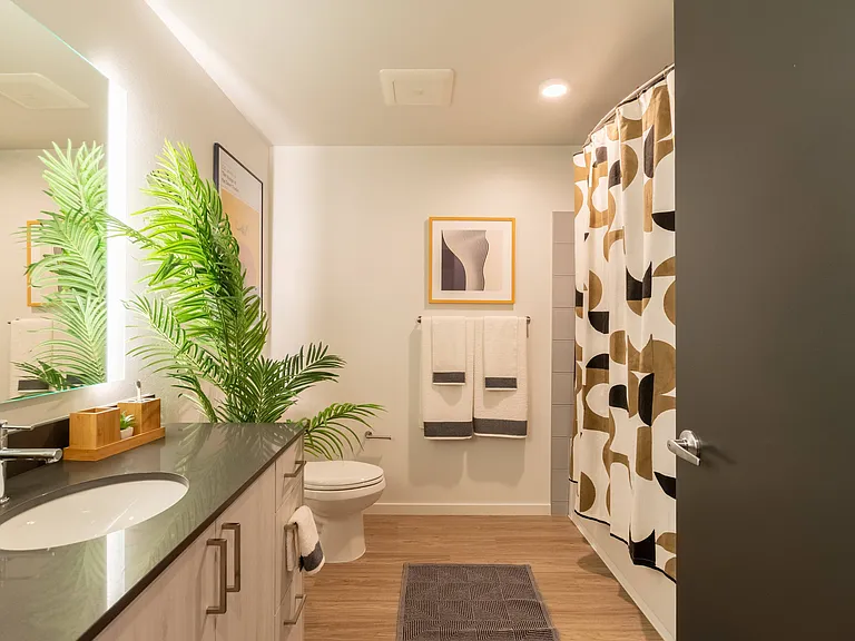 Serene bathrooms with quartz countertops, backlit bathroom mirrors and tile surrounds