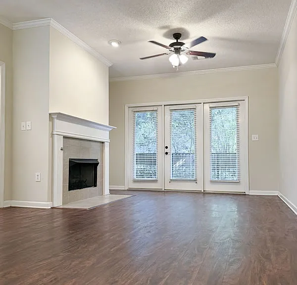 Living area from the dining area featuring a gas fireplace, ceiling fan, and opening onto a small private porch.