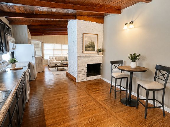 Virtually staged to illustrate possible dining placement; furnishings and decor are not included. Open view toward the decorative fireplace and living room.